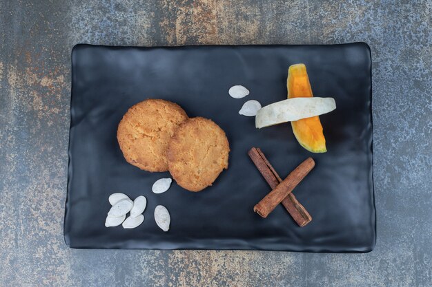 Koekjes, kaneel en plakjes pompoen op zwarte plaat. Hoge kwaliteit foto