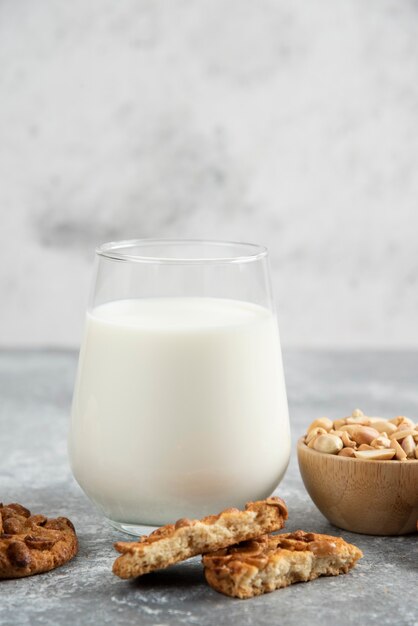 Koekjes met biologische pinda's en honing met glas melk op marmeren tafel.