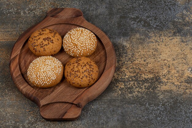 Koekjes met sesamzaadjes en chocoladestukjes op een houten bord.