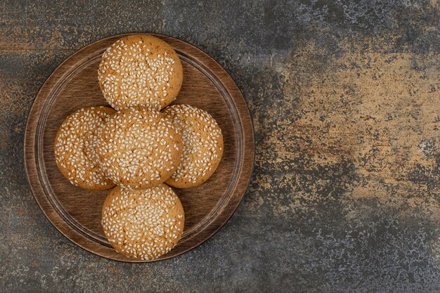 Koekjes met sesamzaadjes op een houten bord.