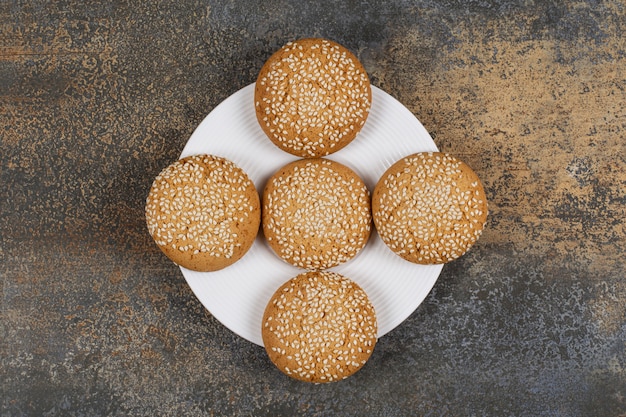 Koekjes met sesamzaadjes op witte plaat.