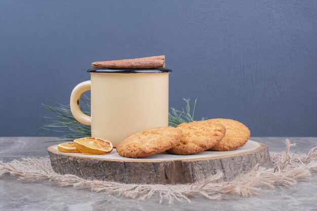 Koekjes op een houten bord met een kopje thee eromheen.