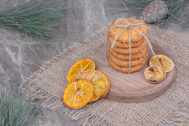 Koekjes op een houten bord met stukjes sinaasappel rond.