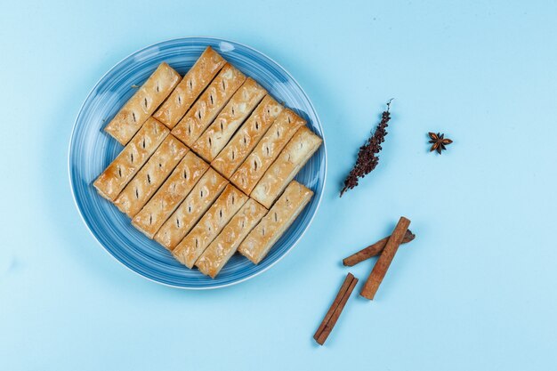 Koekjes op een plaat met gedroogde kruiden en specerijen op blauwe achtergrond