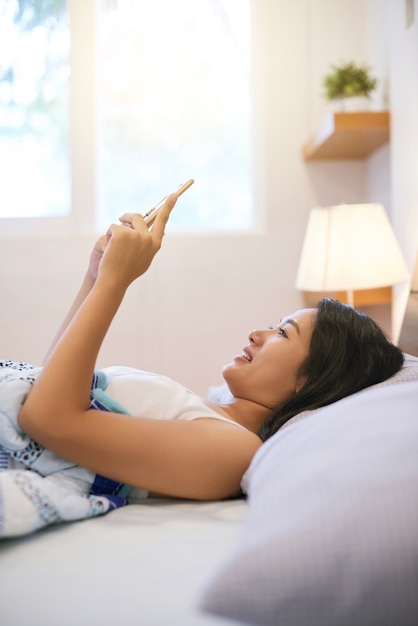 Koele vrouw met telefoon in bed