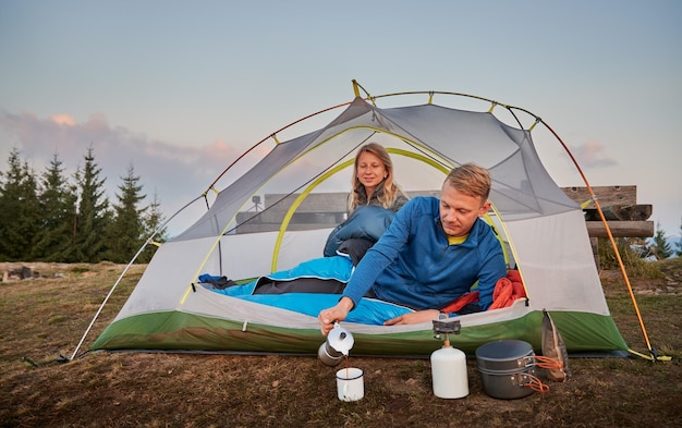 Gratis foto koele zonnige ochtend van kampeerderspaar op bergcamping