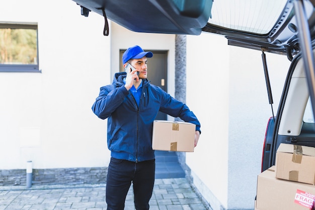 Koerier die op telefoon in binnenplaats spreekt