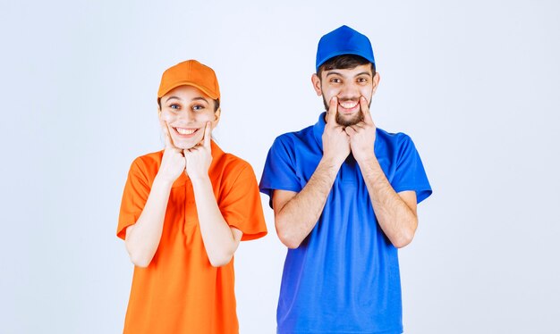 Koerierjongen en -meisje in blauwe en gele uniformen die mooie en vrolijke poses geven.