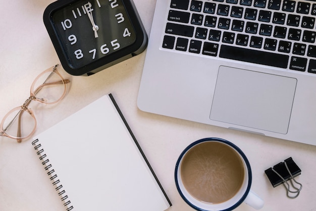 Koffie en briefpapier in de buurt van klok en laptop