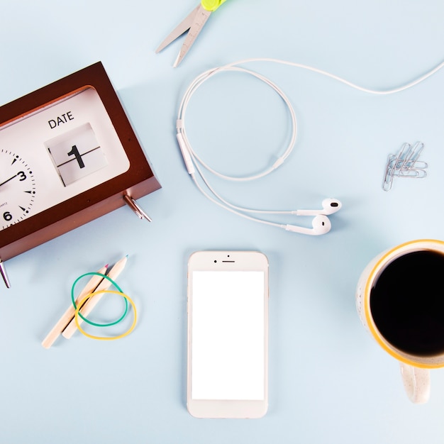 Koffie en smartphone in de buurt van briefpapier en klok