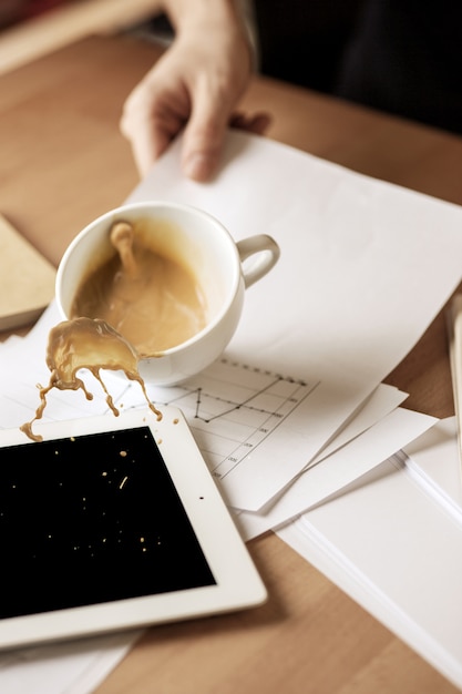 Gratis foto koffie in witte kop die op de lijst in de ochtend bij bureaulijst morsen