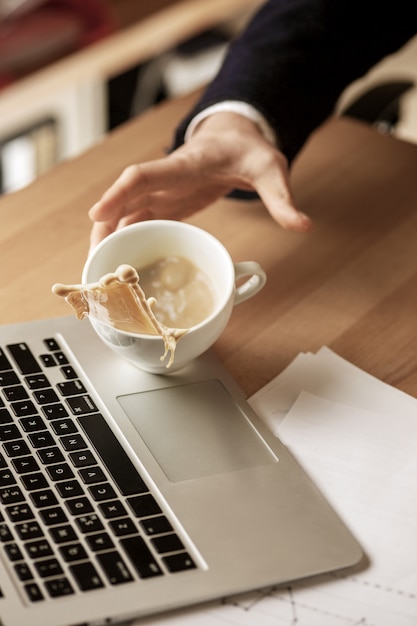 Koffie in witte kop die op de lijst in de ochtend bij bureaulijst morsen