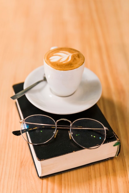 Gratis foto koffie latte en bril over boek