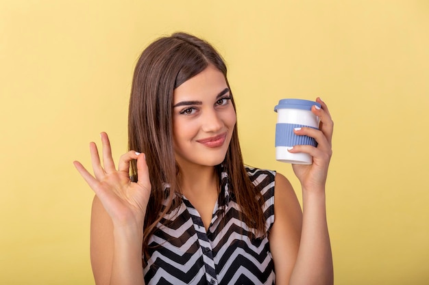 Koffie liefhebber concept. close-up foto portret van heerlijk vrolijk positief met brede stralende glimlach persoon met kopje warme latte in handen knuffelen voor zichzelf geïsoleerde felle kleur achtergrond