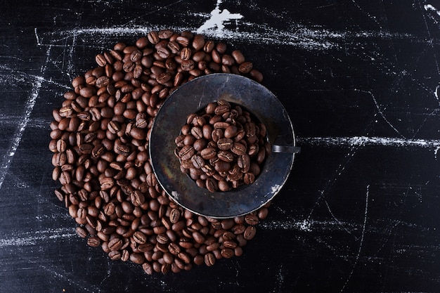 Koffiebonen in de beker en op de grond.