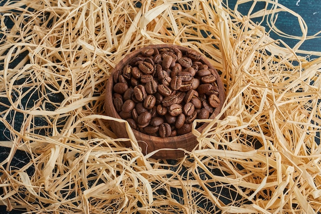 Koffiebonen in een houten kopje op het droge gras.