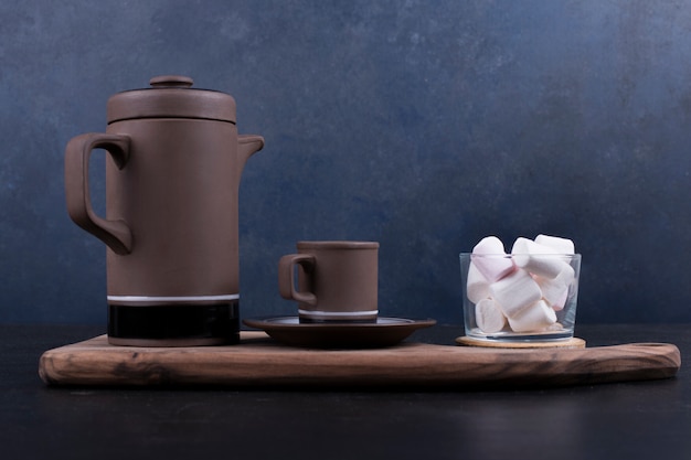 Gratis foto koffieketel met een kop en marshmallows op een houten schotel, profielweergave.