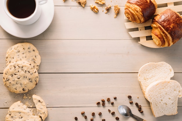 Koffiekop met broodjes en koekjes op houten lijst