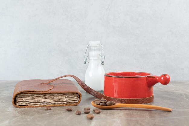 Koffiekopje, bonen en notitieboekje op marmeren tafel.
