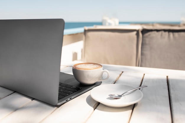 Koffiekopje en laptop aan zee