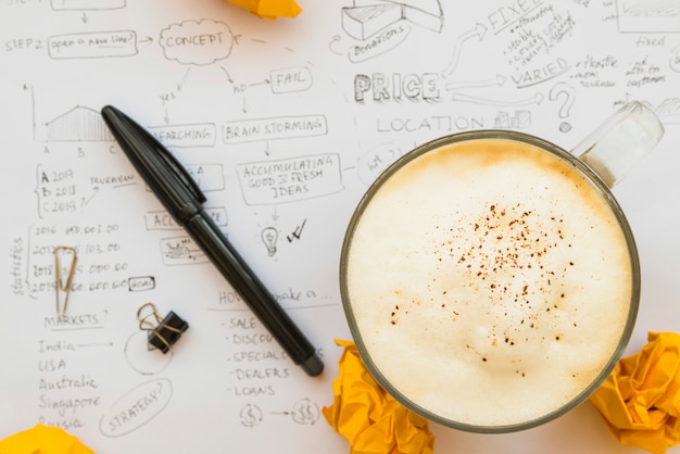 Gratis foto koffiekopje met pen op brainstorm papier blad