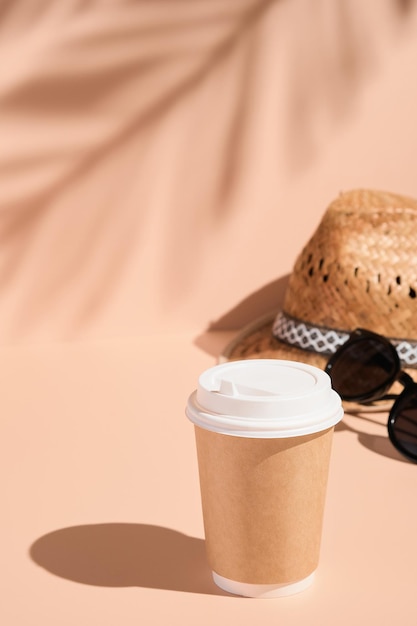 Koffiekopje strohoed en zonnebril op een lichtbeige achtergrond in de schaduw van palmbladeren verticaal frame dromen over zomer en plezier genieten van het leven vakanties vakantie reizen toerisme concept