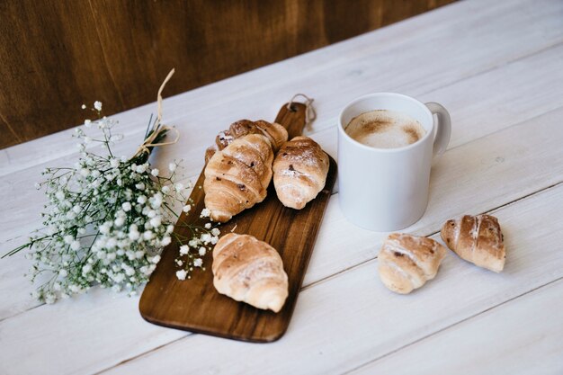 Koffiemok, croissants en boeket bloemen