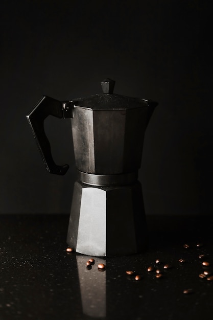 Gratis foto koffiezetapparaat met koffiebonen op zwarte achtergrond