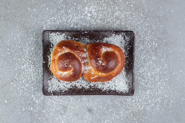 Kokospoeder verspreid op een broodje, een schotel en op een marmeren oppervlak