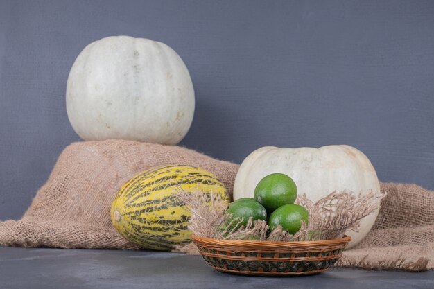 Kom feijoas, witte pompoen en meloen op blauwe muur.