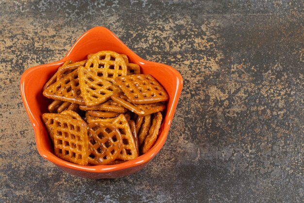 Kom gezouten crackers op marmeren oppervlak.