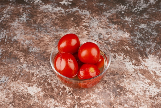 Kom ingelegde tomaten op marmeren oppervlak.