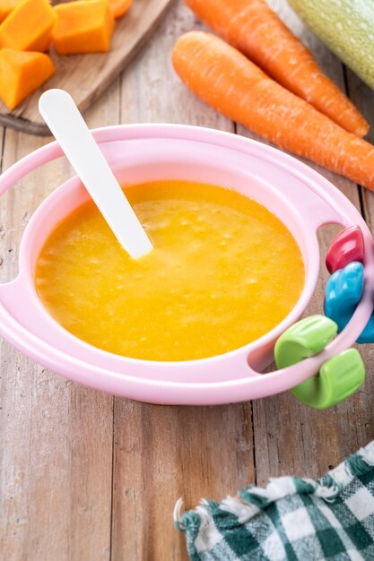 Kom met babyvoeding groente puree op houten tafel