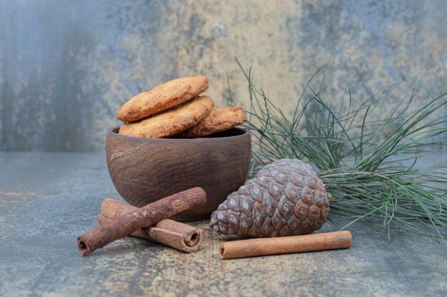 Kom met koekjes, dennenappel en kaneel op marmeren achtergrond. Hoge kwaliteit foto