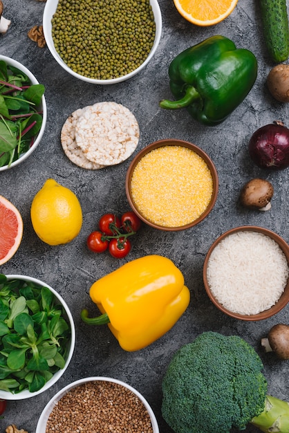 Kom met polenta; rijstkorrels; mung bonen en bladgroenten op concrete achtergrond