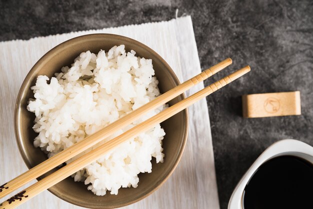 Kom met rijst en eetstokjes op servet dichtbij sojasaus