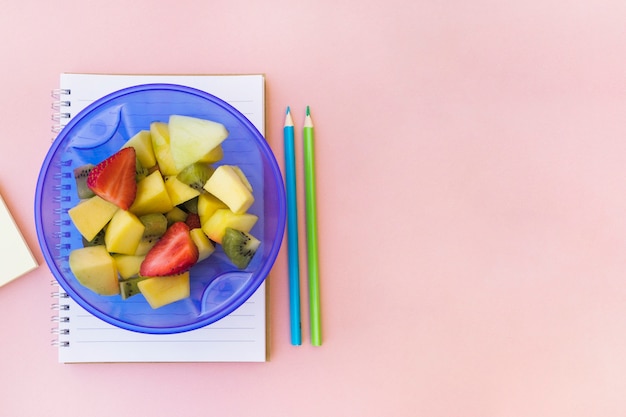 Kom met salade in de buurt van Kladblok en potloden