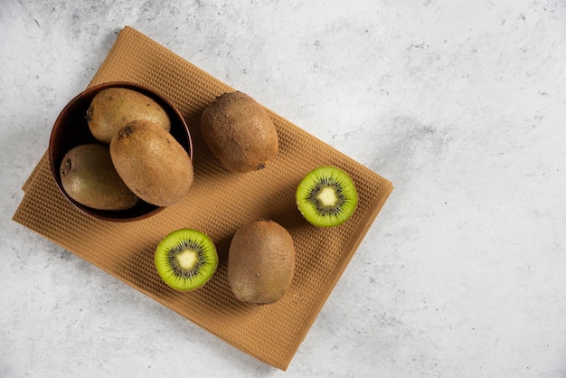 Kom met verse kiwi's op bruin tafellaken Gratis Foto