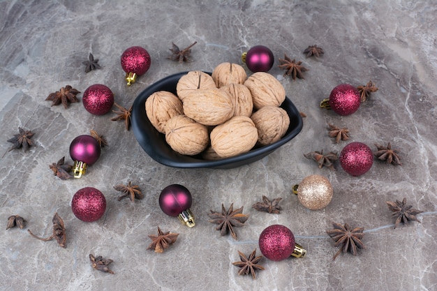 Kom met walnoten met kruidnagel en kerstballen.