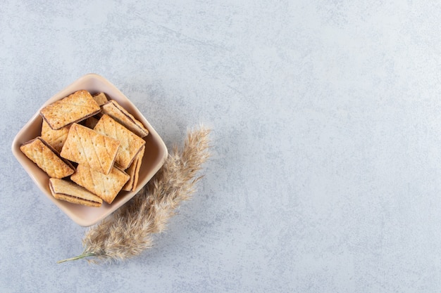 Kom smakelijke crackers gevuld met chocolade op stenen achtergrond.