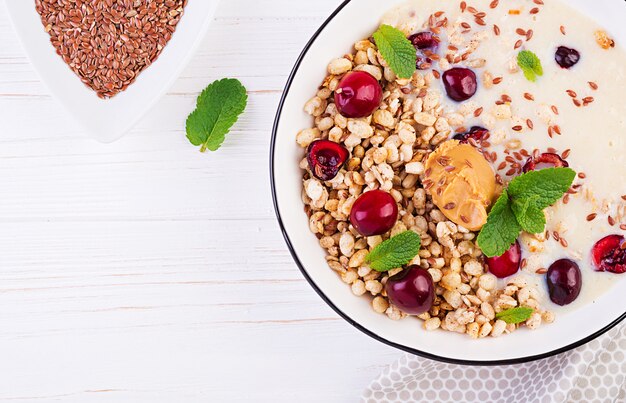 Kom zelfgemaakte muesli met geprakte banaan, pindakaas en verse bessen