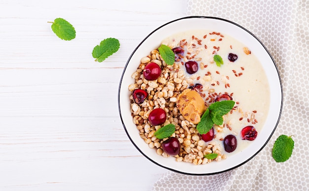 Kom zelfgemaakte muesli met geprakte banaan, pindakaas en verse bessen