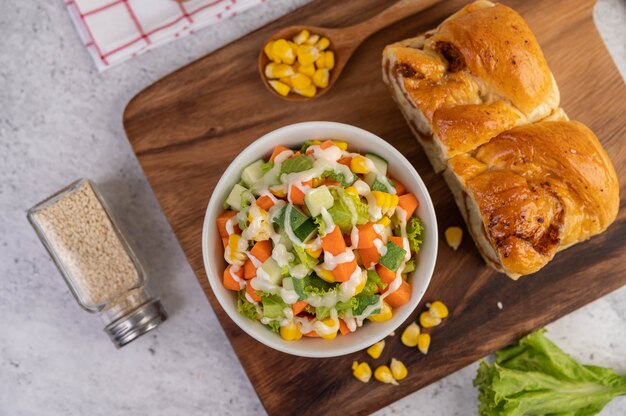 Komkommersalade, maïs, wortel en sla in een witte kop.