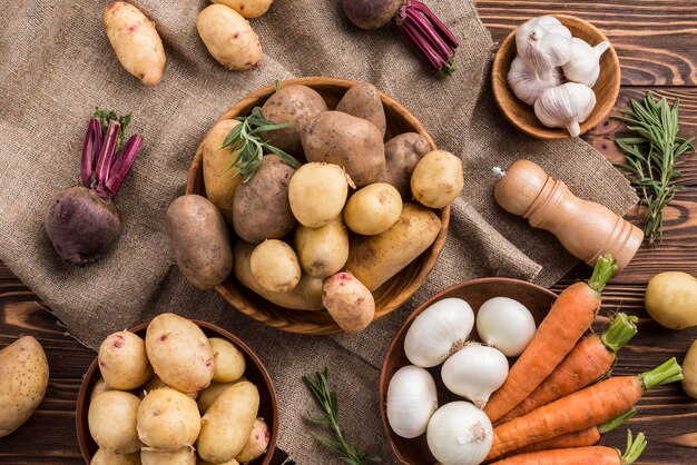 Kommen met aardappelen wortel en knoflook op tafel