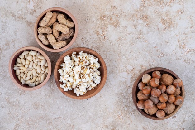 Kommen met hazelnoten, pinda's, zonnebloempitten en popcorn op marmeren oppervlak