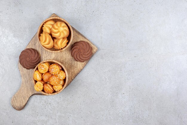 Kommen met koekjes naast bruine koekjes op houten raad op marmeren achtergrond. Hoge kwaliteit foto