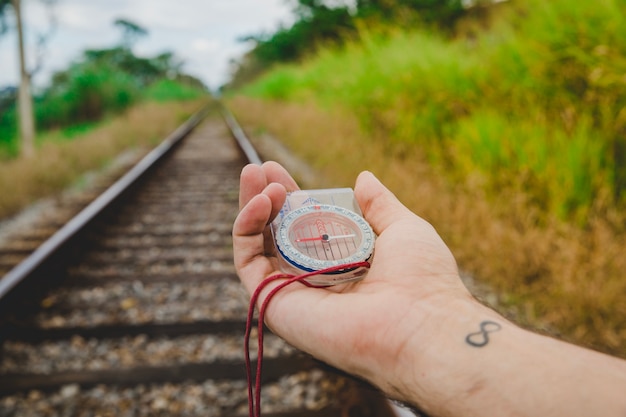 Gratis foto kompas in getatoeëerde hand op treinsporen