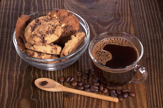 Kop warme koffie en koekjes met chocolade in kom voor ontbijt op houten tafel