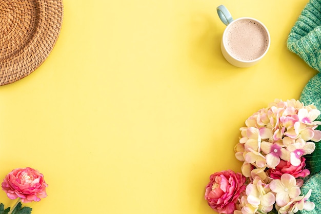 Kopje koffie bloemen en gebreid element op gele achtergrond plat lag