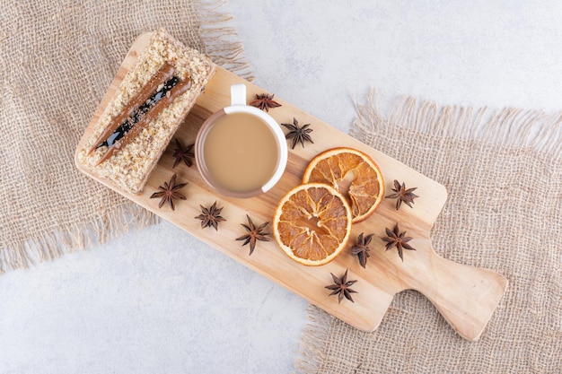 Gratis foto kopje koffie, cake en stukjes sinaasappel op een houten bord. hoge kwaliteit foto